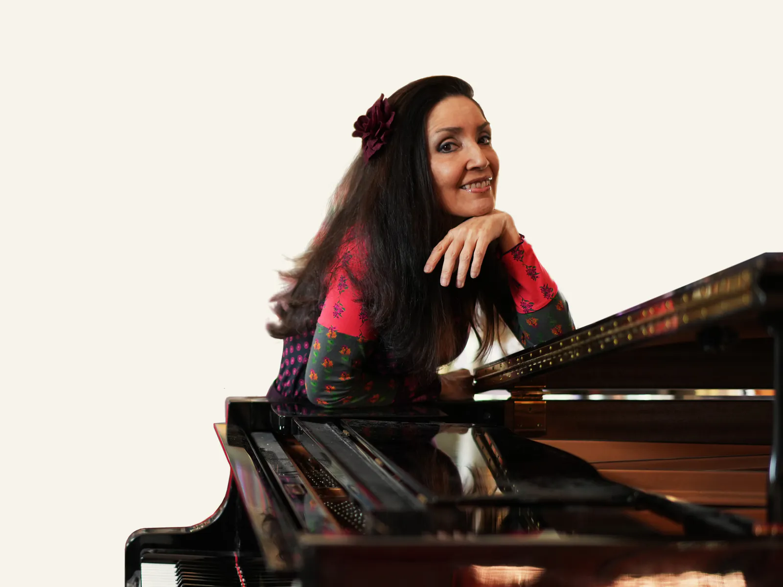 Maria Gabriella Mariani appoggiata a un pianoforte a coda, sorride verso l'obiettivo
